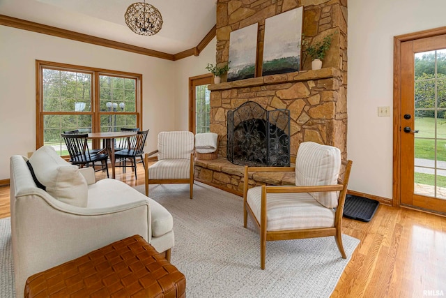 living room featuring a stone fireplace, ornamental molding, light hardwood / wood-style flooring, and lofted ceiling