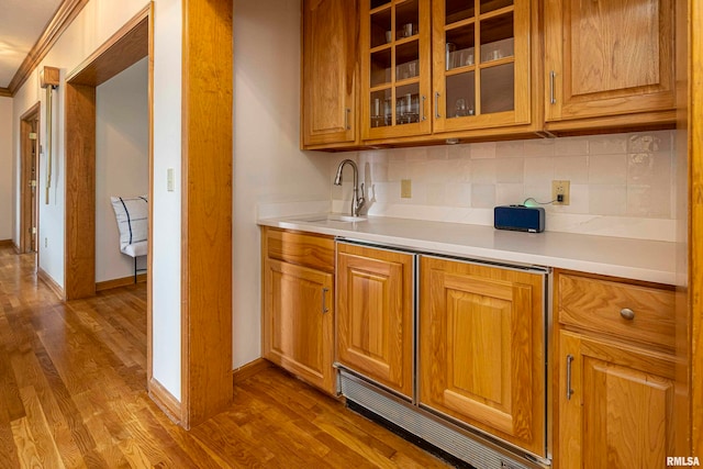 kitchen featuring ornamental molding, hardwood / wood-style flooring, sink, and tasteful backsplash