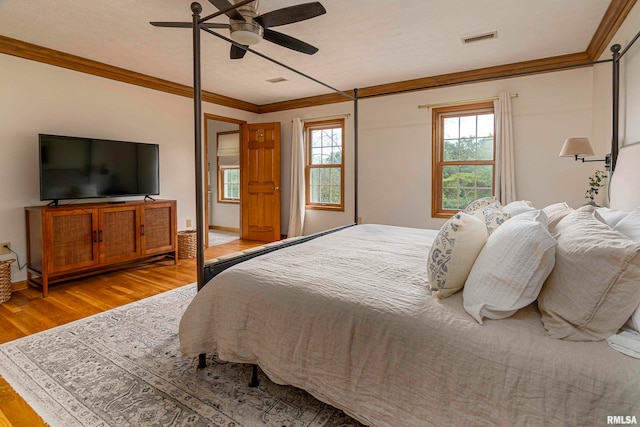 bedroom with light hardwood / wood-style floors, crown molding, a textured ceiling, and ceiling fan