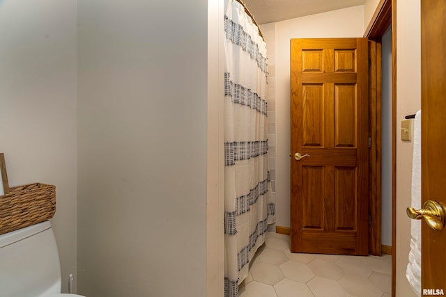 bathroom with toilet, lofted ceiling, tile patterned floors, and a shower with shower curtain