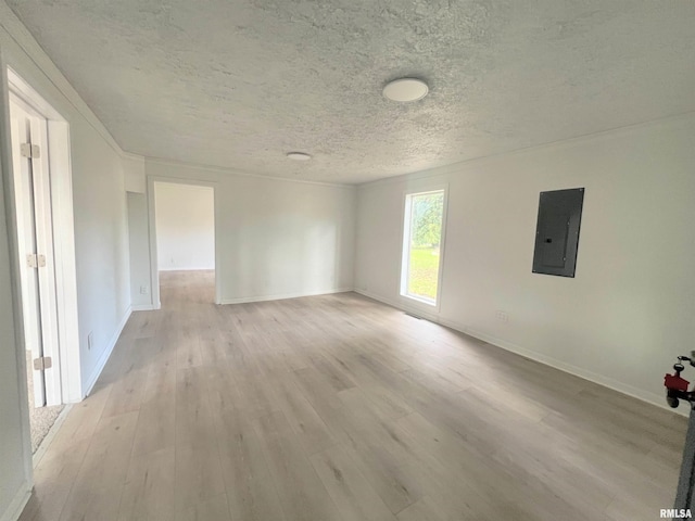 spare room with a textured ceiling, electric panel, and light hardwood / wood-style floors