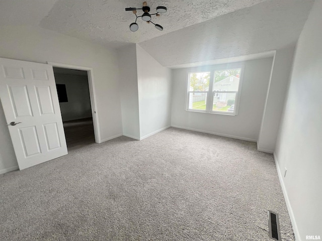 carpeted empty room with lofted ceiling and a textured ceiling