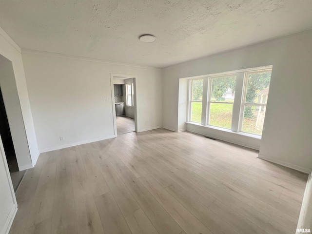 empty room featuring light hardwood / wood-style floors, ornamental molding, and a textured ceiling