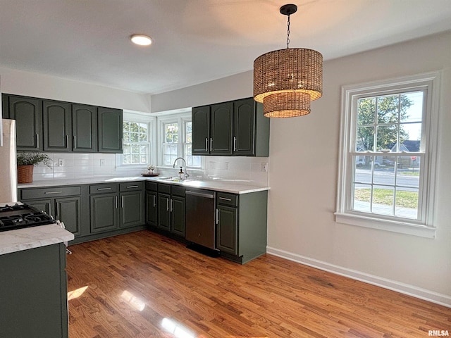 kitchen featuring light hardwood / wood-style floors, decorative backsplash, decorative light fixtures, and stainless steel dishwasher