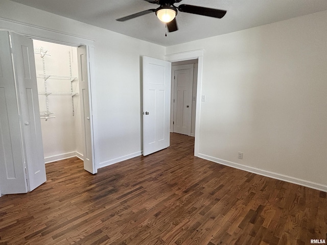 unfurnished bedroom featuring a ceiling fan, baseboards, a spacious closet, a closet, and dark wood-style floors