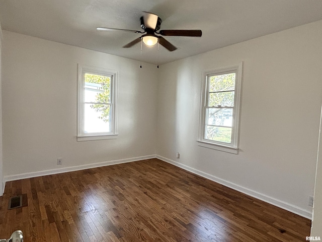 spare room featuring dark wood-style flooring, a wealth of natural light, and baseboards