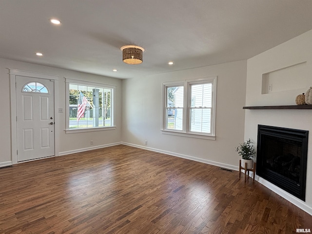 foyer featuring baseboards, visible vents, dark wood finished floors, a fireplace, and recessed lighting