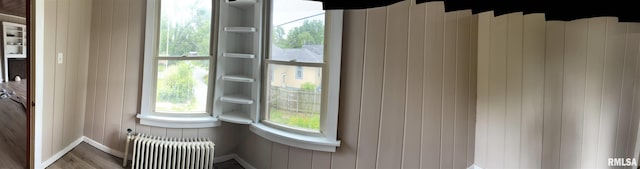 room details with radiator, hardwood / wood-style flooring, and wood walls