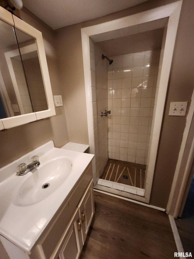 bathroom with vanity, a tile shower, and wood-type flooring