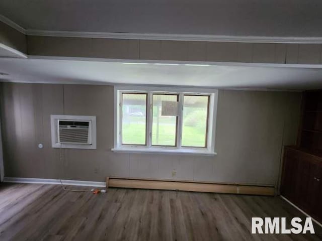 spare room with a baseboard radiator, a wall mounted air conditioner, and hardwood / wood-style flooring