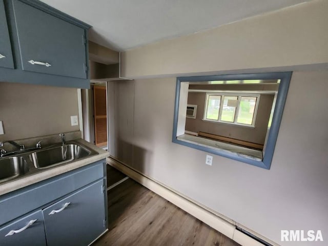 kitchen with a wall mounted AC, dark hardwood / wood-style floors, baseboard heating, sink, and blue cabinetry