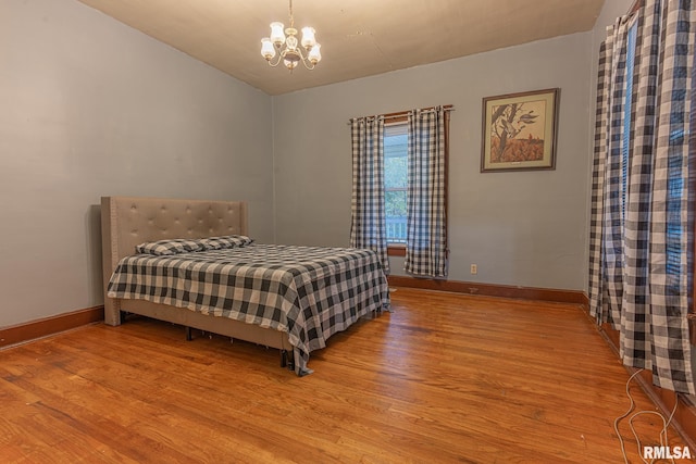 bedroom with light hardwood / wood-style floors and a notable chandelier