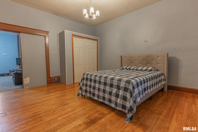 bedroom with an inviting chandelier, wood-type flooring, and a closet