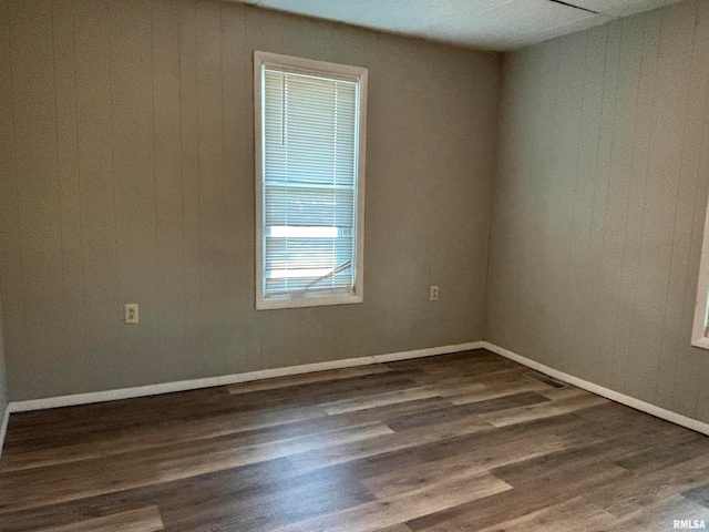 spare room with wooden walls and dark hardwood / wood-style flooring