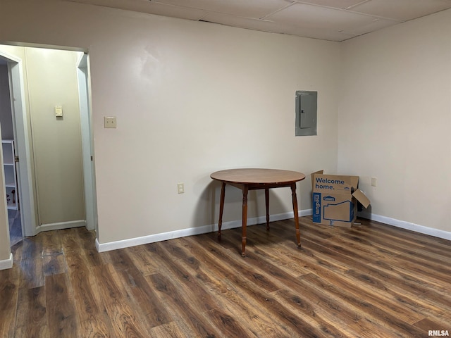 unfurnished room featuring a drop ceiling, electric panel, and dark wood-type flooring