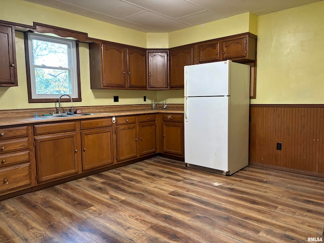 kitchen with white fridge, sink, wooden walls, and dark hardwood / wood-style flooring