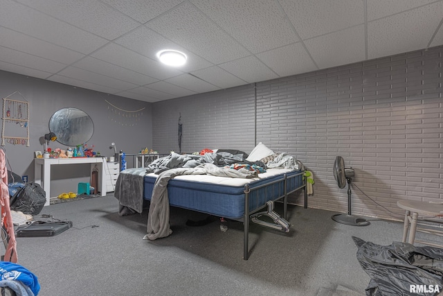 bedroom with brick wall, a drop ceiling, and carpet floors