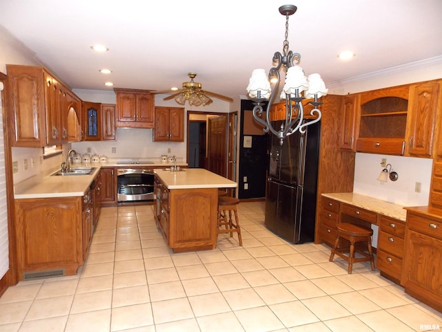 kitchen featuring black fridge, a breakfast bar area, oven, an island with sink, and sink