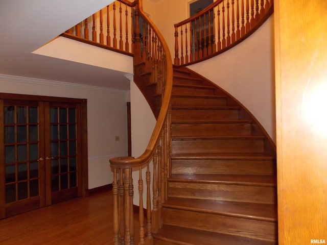 stairway with ornamental molding, french doors, and hardwood / wood-style floors