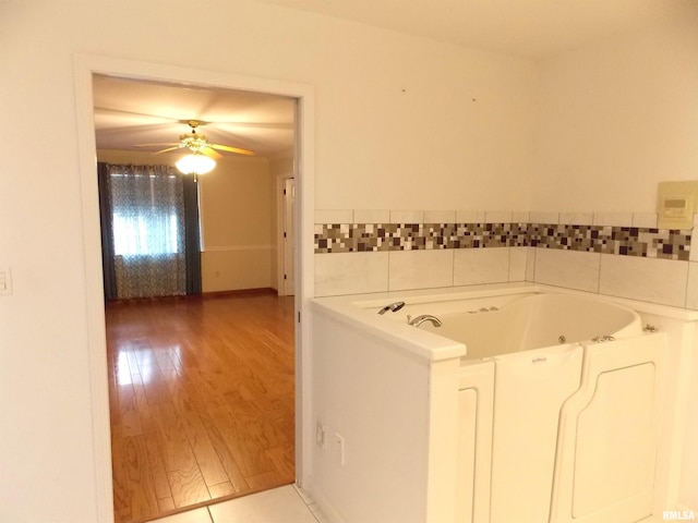 bathroom featuring wood-type flooring, a bath, and ceiling fan