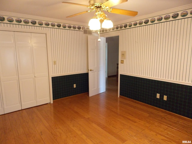 unfurnished bedroom featuring hardwood / wood-style floors, crown molding, and a closet