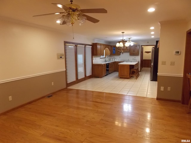 kitchen with stainless steel fridge, hanging light fixtures, sink, light hardwood / wood-style floors, and a center island