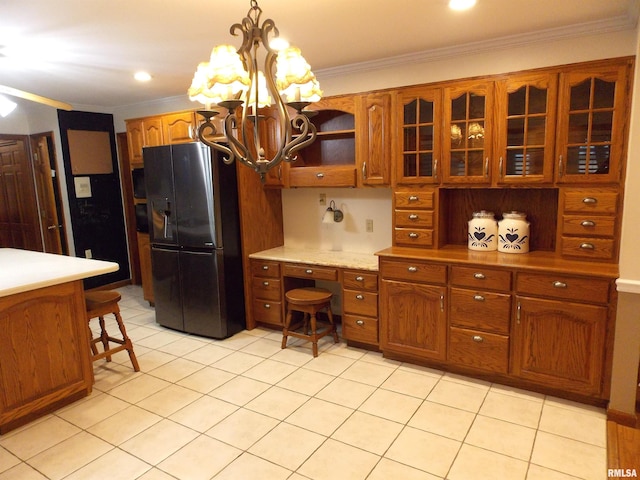 kitchen with stainless steel fridge, decorative light fixtures, crown molding, light tile patterned floors, and an inviting chandelier