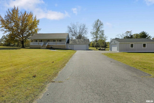 view of front facade featuring covered porch, a garage, a front lawn, and an outdoor structure