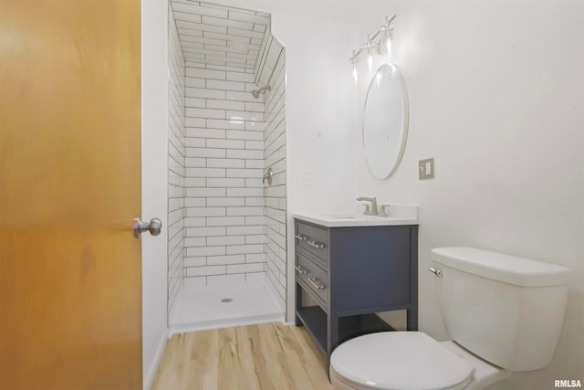 bathroom featuring toilet, hardwood / wood-style floors, vanity, and tiled shower