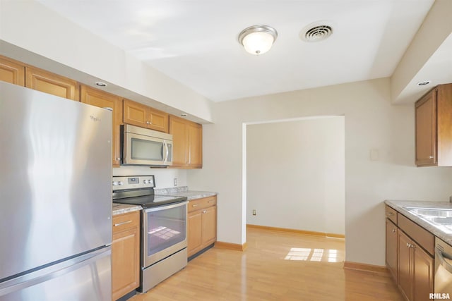 kitchen featuring appliances with stainless steel finishes, sink, and light wood-type flooring