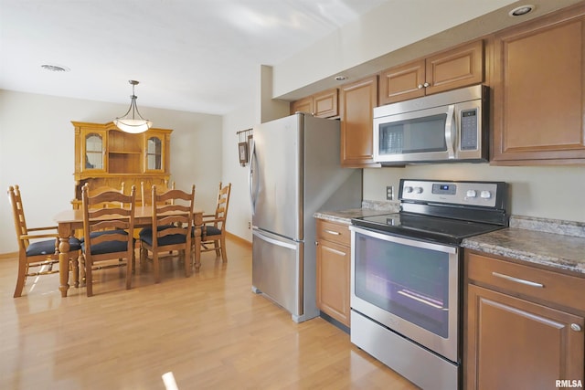 kitchen featuring stainless steel appliances, light wood-type flooring, and pendant lighting