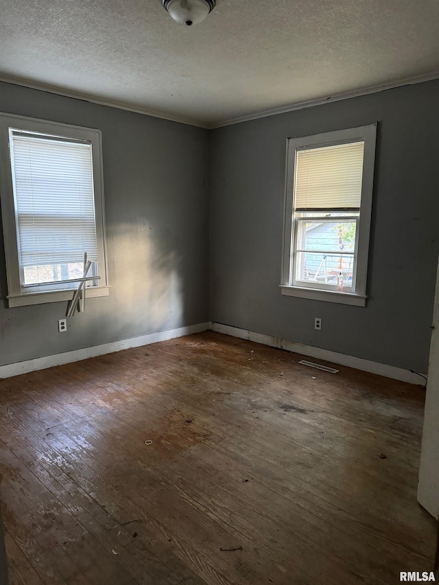 spare room with crown molding, a textured ceiling, and dark hardwood / wood-style floors