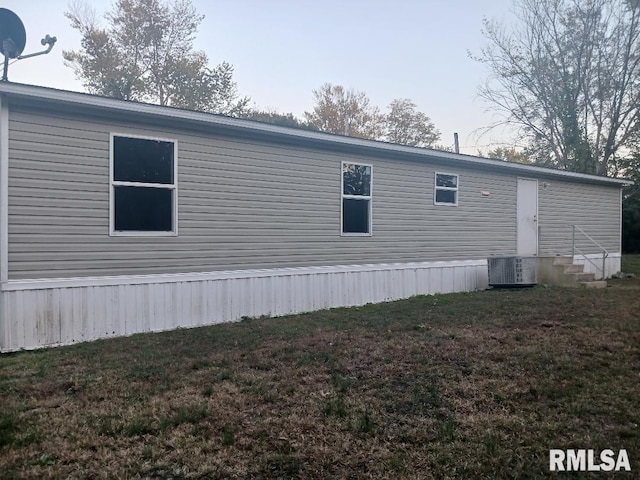 view of property exterior with central AC and a yard