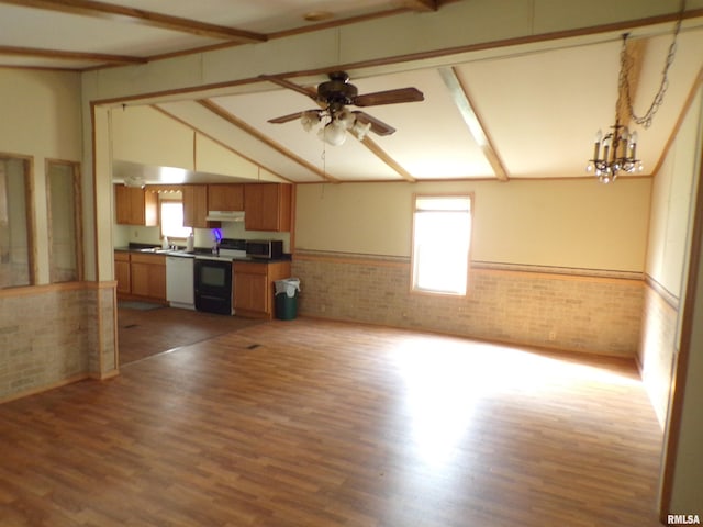 unfurnished living room featuring hardwood / wood-style floors, vaulted ceiling, ceiling fan with notable chandelier, and plenty of natural light