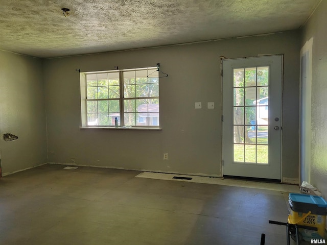 doorway to outside with a textured ceiling