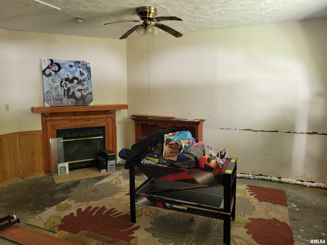 living room featuring wooden walls, concrete flooring, a textured ceiling, and ceiling fan