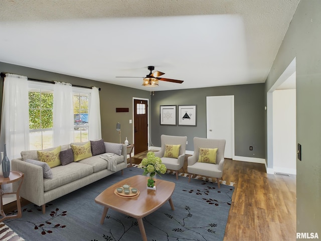 living room featuring dark hardwood / wood-style floors, a textured ceiling, and ceiling fan