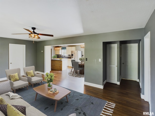 living room featuring ceiling fan, sink, and dark hardwood / wood-style floors