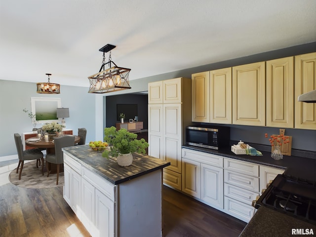 kitchen with dark wood-type flooring, a center island, black range oven, and hanging light fixtures