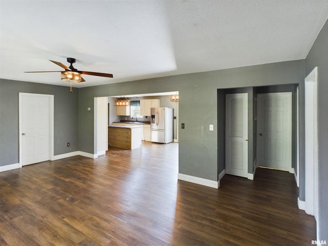 unfurnished living room featuring sink, dark hardwood / wood-style floors, a textured ceiling, and ceiling fan