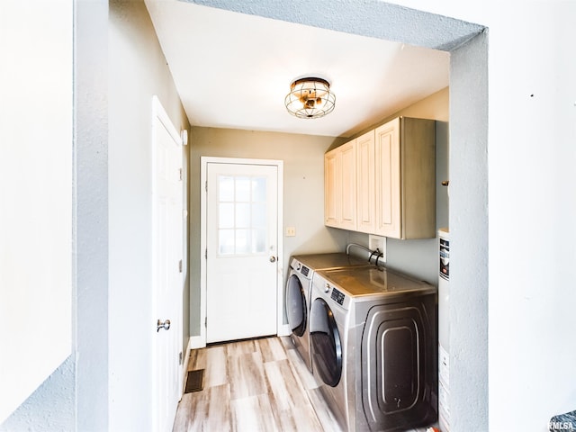 laundry area with light hardwood / wood-style flooring, washing machine and clothes dryer, and cabinets