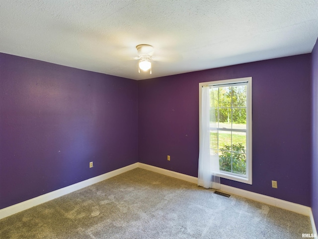 spare room with a textured ceiling, ceiling fan, and carpet floors