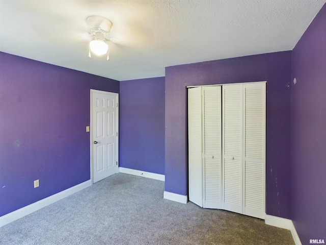 unfurnished bedroom featuring a textured ceiling, carpet floors, a closet, and ceiling fan