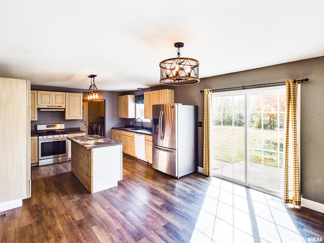 kitchen featuring sink, a center island, dark hardwood / wood-style flooring, hanging light fixtures, and stainless steel appliances