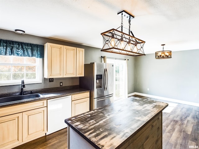 kitchen with dishwasher, dark wood-type flooring, sink, stainless steel fridge, and decorative light fixtures