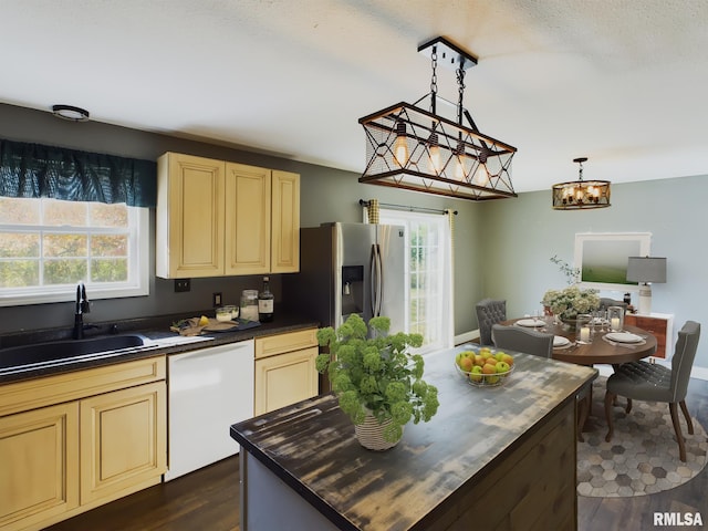 kitchen featuring dishwasher, cream cabinets, hanging light fixtures, sink, and dark hardwood / wood-style flooring