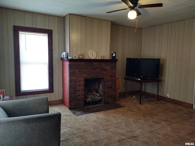 carpeted living room featuring ceiling fan, wood walls, and a brick fireplace