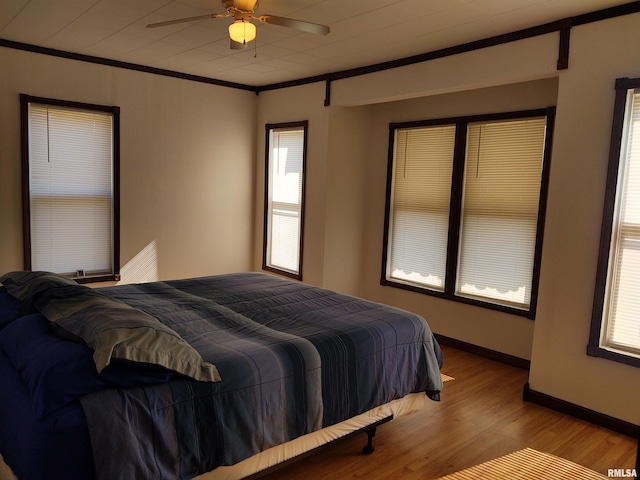 bedroom featuring ceiling fan, ornamental molding, and light hardwood / wood-style flooring