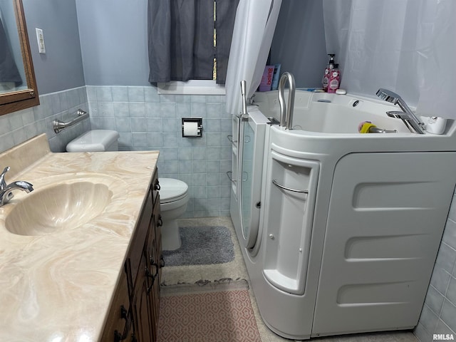 bathroom with washer / dryer, toilet, tile walls, vanity, and a bathtub