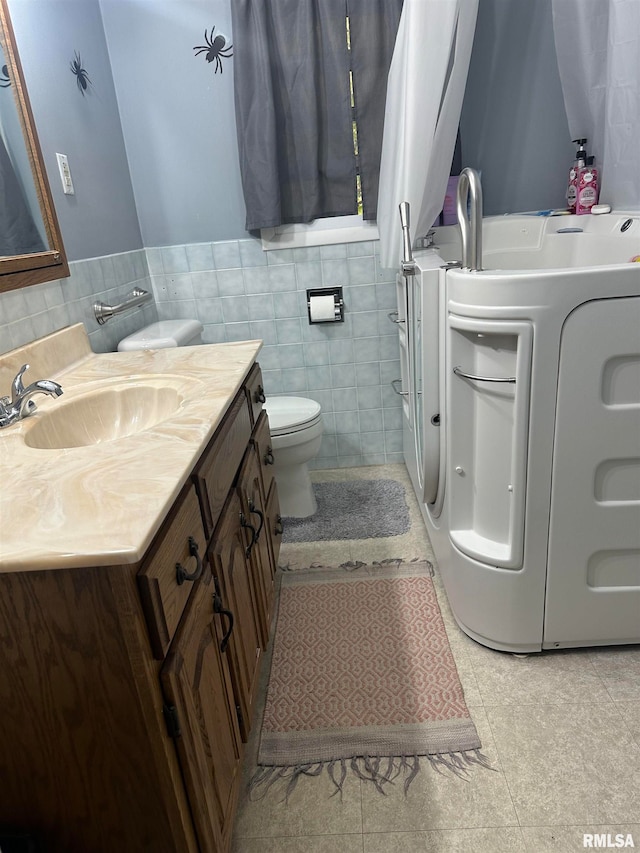 bathroom featuring tile walls, toilet, independent washer and dryer, vanity, and tile patterned flooring